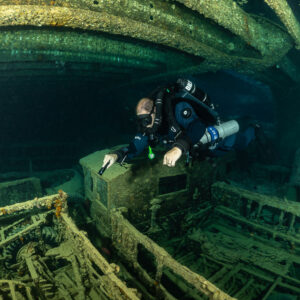 Rebreather diver leaning over truck side rails in a cargo hold, Thistlegorm wreck, Red Sea, Egypt