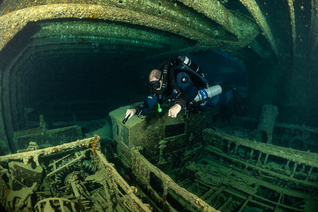 Rebreather diver leaning over truck side rails in a cargo hold, Thistlegorm wreck, Red Sea, Egypt
