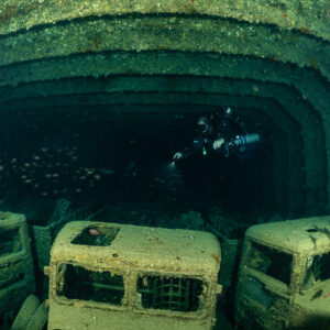 Rebreather diver above a row of three truck cabs in a hold, Thistlegorm wreck, Red Sea, Egypt