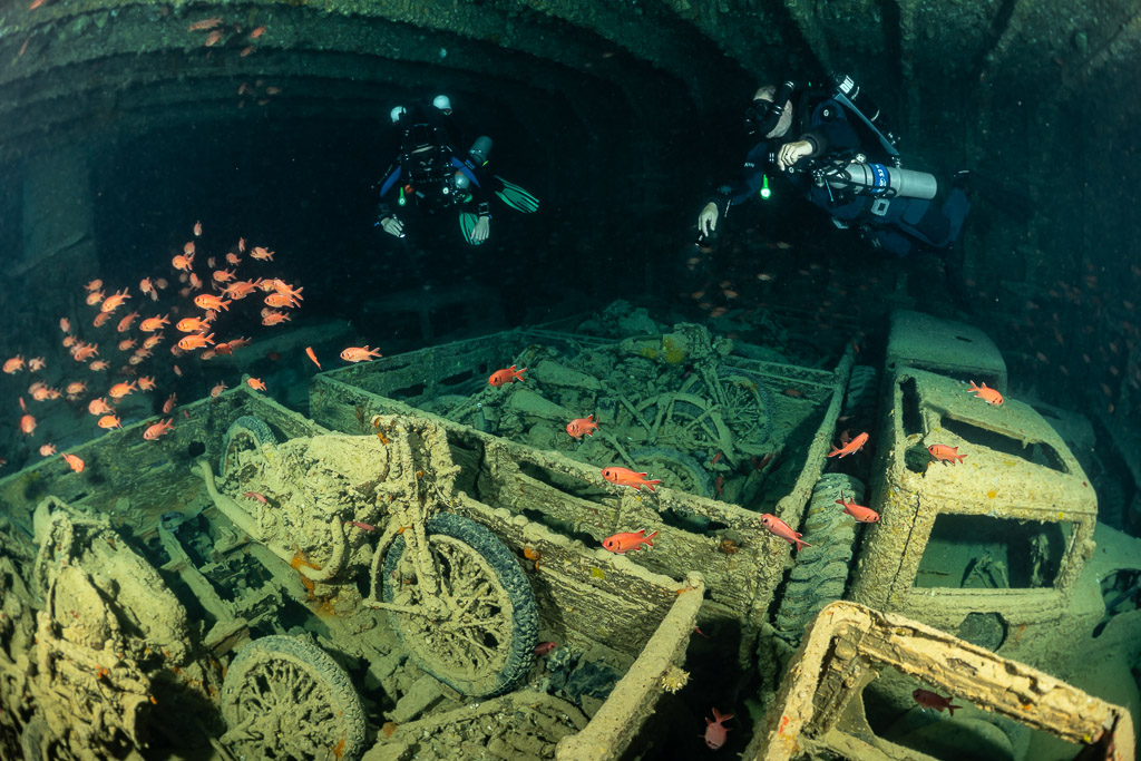 Two rebreather divers above motorcycles in truck beds with soldierfish, Thistlegorm wreck, Red Sea, Egypt