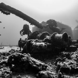 Black-and-white view of two divers over a deck winch on a wreck, Thistlegorm wreck, Red Sea, Egypt