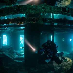 Rebreather diver with torch among pillars of a flooded wreck deck, Thistlegorm wreck, Red Sea, Egypt