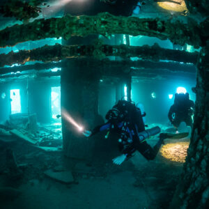 Rebreather diver among wreck pillars with a second diver beyond, Thistlegorm wreck, Red Sea, Egypt