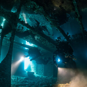 Two rebreather divers in a wreck interior with blue light and silt, Thistlegorm wreck, Red Sea, Egypt