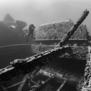 Black-and-white view of a diver beyond broken beams on a wreck deck, Thistlegorm wreck, Red Sea, Egypt