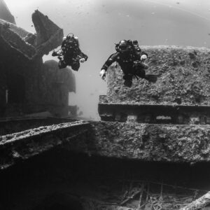 Black-and-white shot of two rebreather divers beside a wreck superstructure, Thistlegorm wreck, Red Sea, Egypt