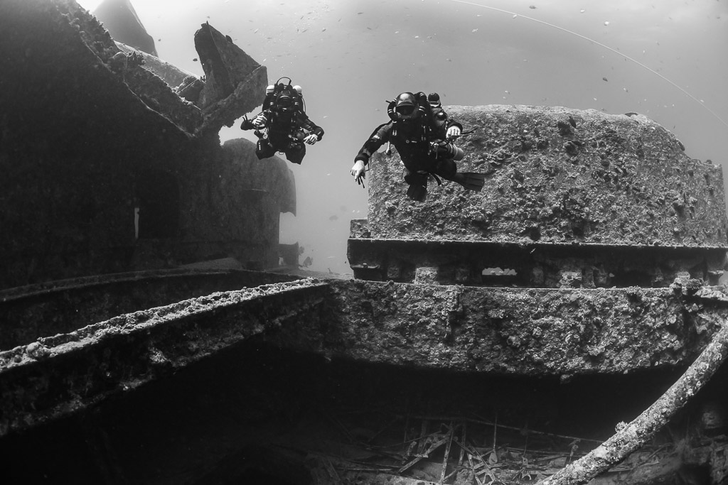 Black-and-white shot of two rebreather divers beside a wreck superstructure, Thistlegorm wreck, Red Sea, Egypt