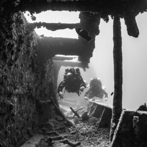 Black-and-white shot of two divers approaching in a wreck corridor, vertical, Thistlegorm wreck, Red Sea, Egypt