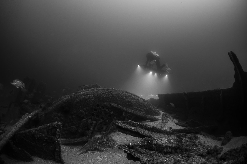 Black and white rebreather diver lighting broken wreck plates with photogrammetry rig, Saint-Malo, Brittany, France