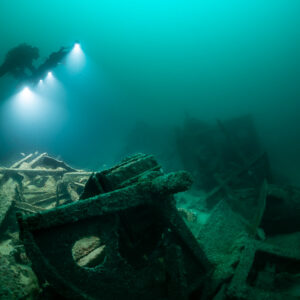 Diver surveying tangled wreck machinery with a pierced steel plate in foreground, Saint-Malo, Brittany, France