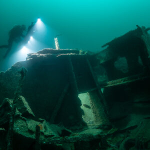 Diver passing behind a boxy wreck structure with lit photogrammetry rig, Saint-Malo, Brittany, France
