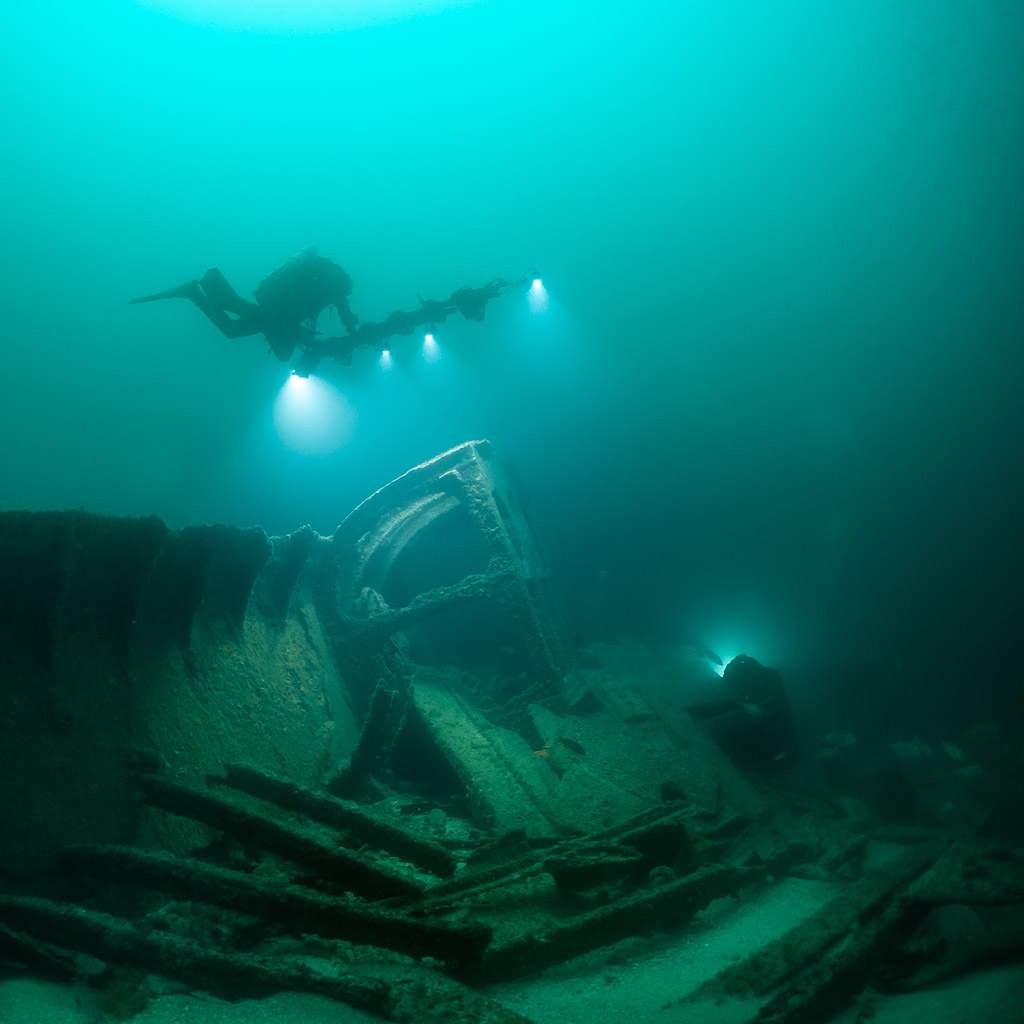 Two divers with lights exploring collapsed wreck frames, vertical framing, Saint-Malo, Brittany, France