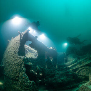Divers and light beams behind a twisted wreck plate, vertical framing, Saint-Malo, Brittany, France