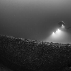 Black and white diver above a long curved encrusted wreck section, Saint-Malo, Brittany, France