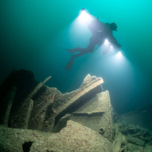 Diver in red fins above stacked wreck plates, vertical framing, Saint-Malo, Brittany, France