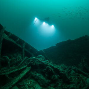 Distant diver lights framed between two broken wreck hull sides, Saint-Malo, Brittany, France