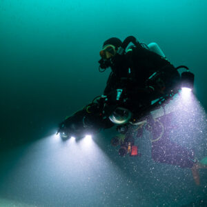 Close portrait of rebreather diver holding photogrammetry rig, particles in beams, Saint-Malo, Brittany, France