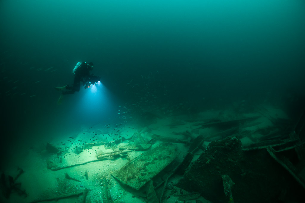 Small distant diver lighting a wide wreck debris field, Saint-Malo, Brittany, France