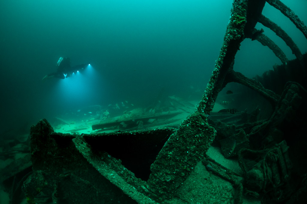 Diver lights in distance beyond an encrusted wreck frame in foreground, Saint-Malo, Brittany, France