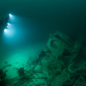Diver above a boxy wreck structure lighting the seabed, Saint-Malo, Brittany, France