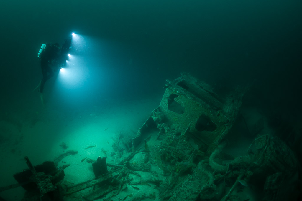 Diver above a boxy wreck structure lighting the seabed, Saint-Malo, Brittany, France