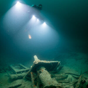 Diver lighting a cylindrical wreck fitting, vertical framing, Saint-Malo, Brittany, France