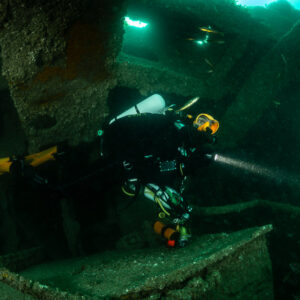 Rebreather diver with torch and yellow fins inside the Laplace wreck, Laplace wreck, Brittany, France