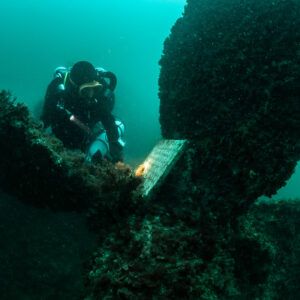 Rebreather diver close behind the propeller and memorial plaque, Laplace wreck, Brittany, France