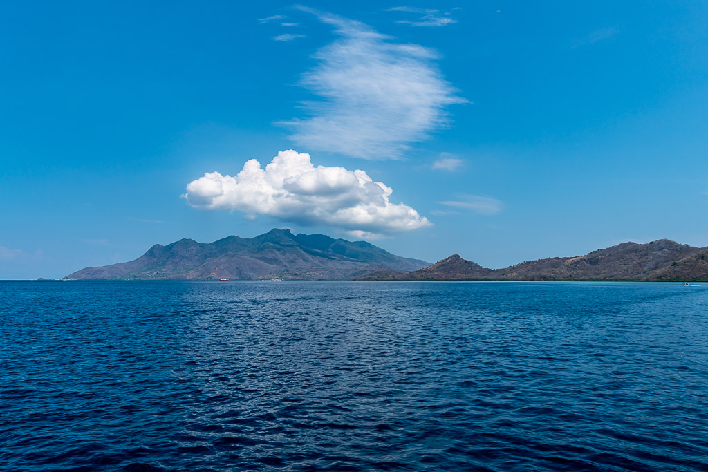 Île volcanique sous des nuages blancs vue depuis la mer, West Flores, mer de Banda, Indonésie