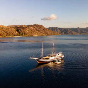 Aerial view of a phinisi liveaboard anchored in a bay at sunset, Kawula, Banda Sea, Indonesia