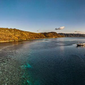 Aerial panorama of a bay with fringing reef and anchored phinisi, Bacatan Wall, Banda Sea, Indonesia