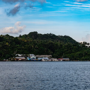 Village côtier au pied de collines boisées sous un ciel bleu, îles Banda, mer de Banda, Indonésie