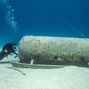 Diver examining a sunken cylindrical chamber on its cradle, Grand Bahama, Bahamas