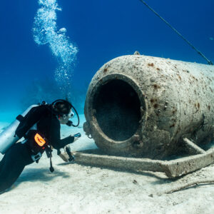 Diver beside the open hatch of a sunken cylindrical chamber, Grand Bahama, Bahamas