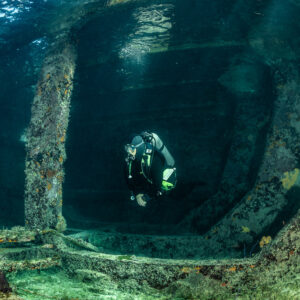 Diver descending between wreck walls and pillars, front view, SS Sapona wreck, Bimini, Bahamas