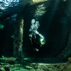 Diver exhaling bubbles in wreck compartment with soft sunbeams, SS Sapona wreck, Bimini, Bahamas
