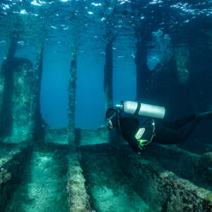 Diver gliding over wreck ribs with pillars in the background, SS Sapona wreck, Bimini, Bahamas