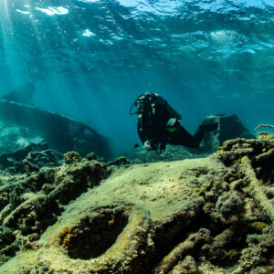 Diver behind wreck debris and cables, sunbeams from the surface, SS Sapona wreck, Bimini, Bahamas