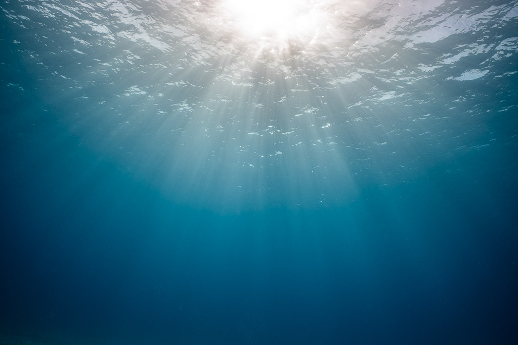 Sunburst and light rays under the surface in deep blue water, Bimini, Bahamas