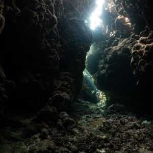 Light filtering through a narrow crack into a dark reef cave, Zabargad, Red Sea, Egypt