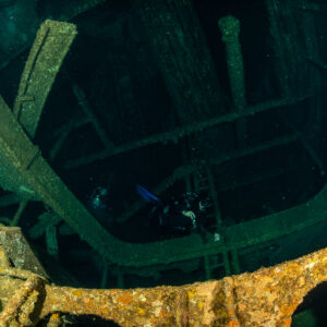 Diver deep inside the dark frames of a wreck interior, Levanzo wreck, Red Sea, Egypt