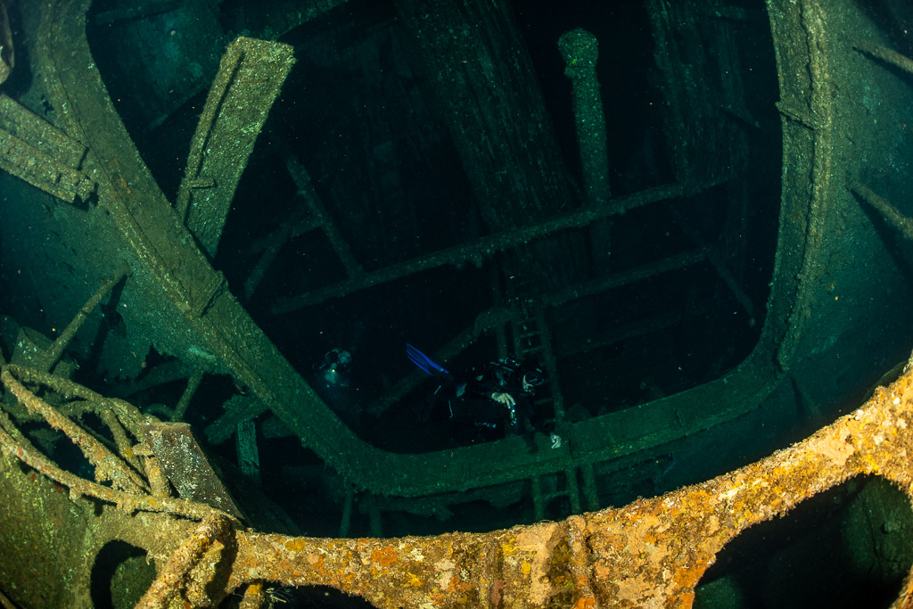 Diver deep inside the dark frames of a wreck interior, Levanzo wreck, Red Sea, Egypt