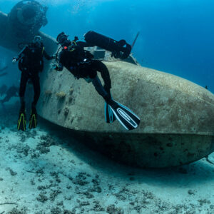 Divers with scooter leaning on the hull of a seaplane wreck, Grumman HU-16 Albatross wreck, Red Sea, Egypt