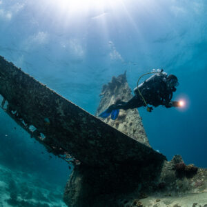 Diver with torch beside the tail fin of a seaplane wreck, Grumman HU-16 Albatross wreck, Red Sea, Egypt