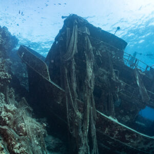 Net-draped bridge of a wreck lying against a reef, Sabri Baba 1 wreck, Red Sea, Egypt