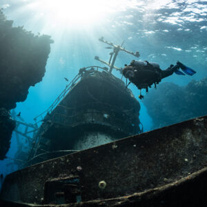 Diver above the mast of a wreck backlit by the sun, Sabri Baba 1 wreck, Red Sea, Egypt
