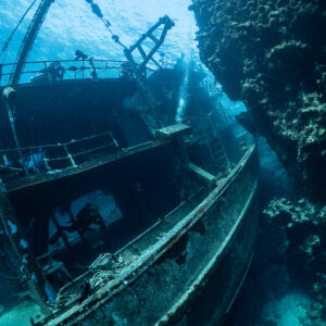 Wreck with masts and davits beside a reef wall, vertical, Sabri Baba 1 wreck, Red Sea, Egypt