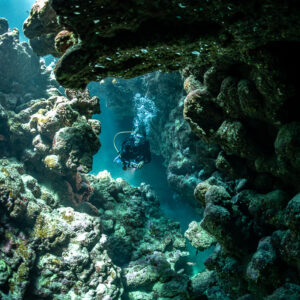 Diver seen through rocky cave opening, Shaab Claudio, Red Sea, Egypt