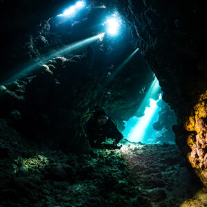 Two torch beams and blue opening in cave, alternate vertical, Shaab Claudio, Red Sea, Egypt