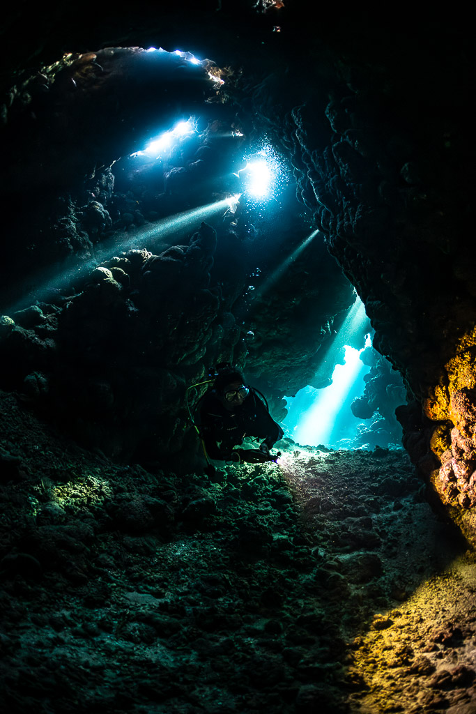 Two torch beams and blue opening in cave, alternate vertical, Shaab Claudio, Red Sea, Egypt
